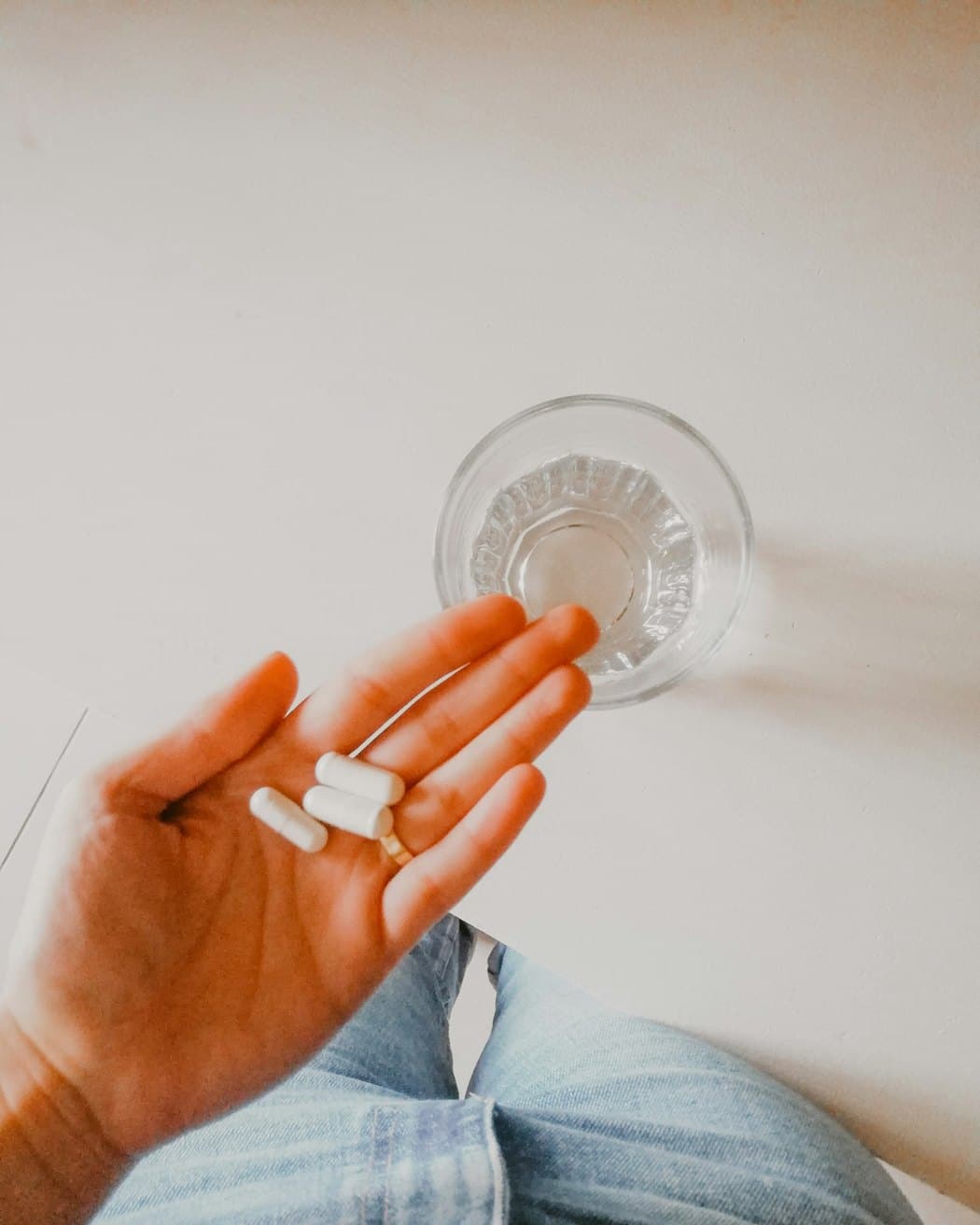 A person taking their prescribed medication with a glass of water