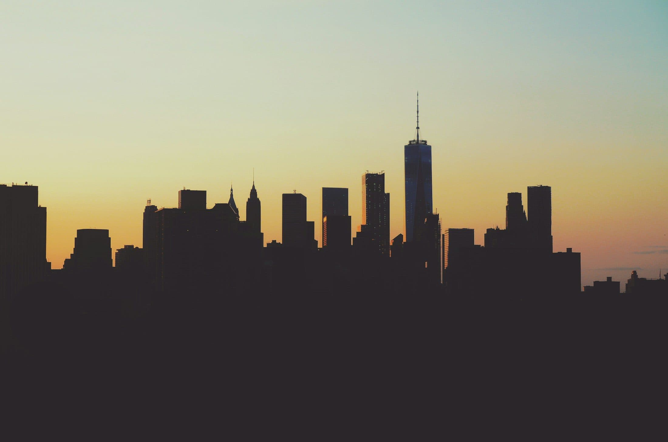 The Manhattan skyline at sunset, One World Trade Center against a warm sky
